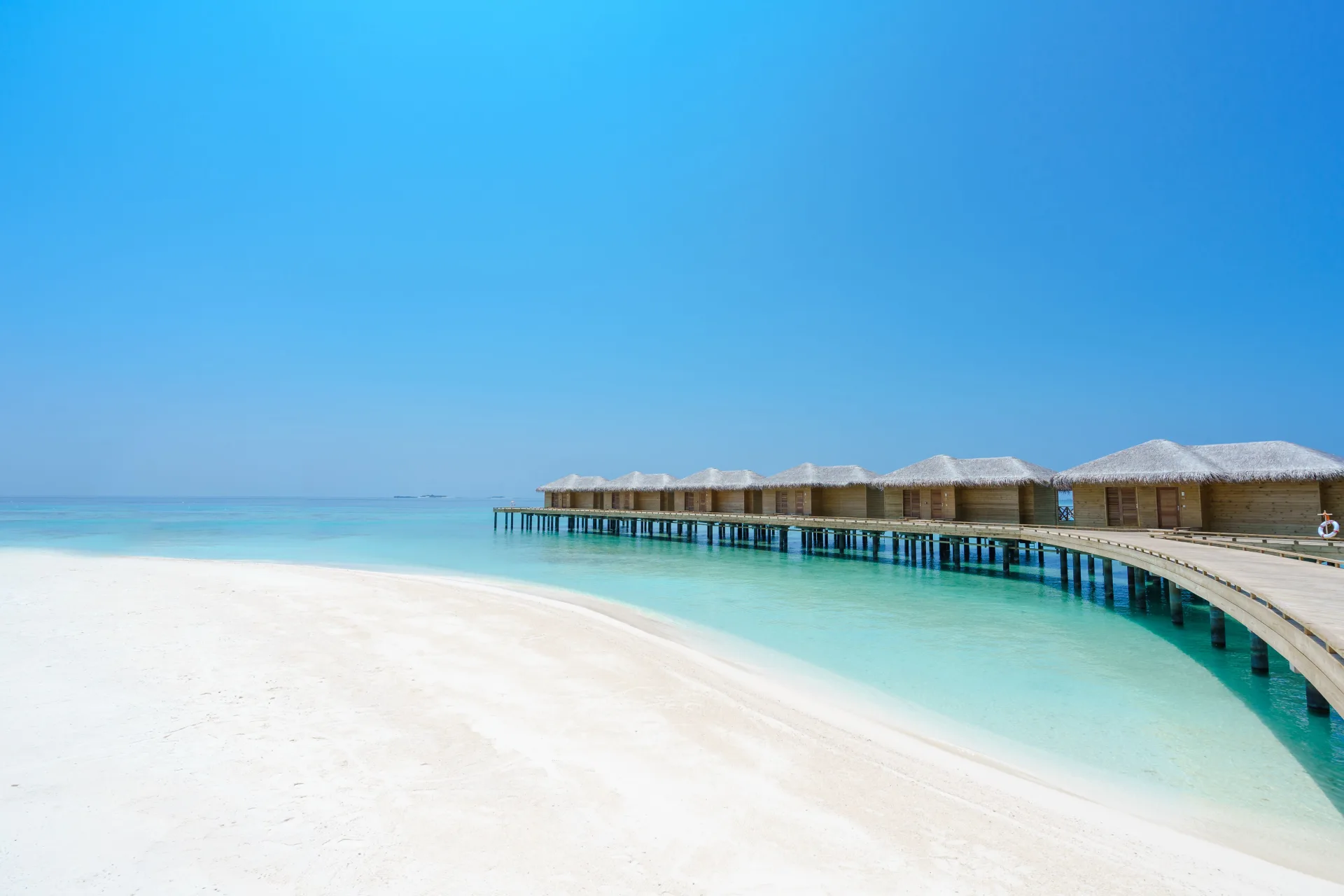 White sandy beach and turquoise lagoon beside overwater bungalows